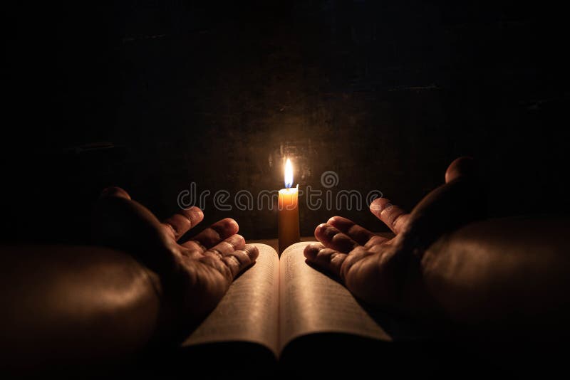 Men praying on the Bible in the light candles selective focus. Beautiful gold background. Religion concept