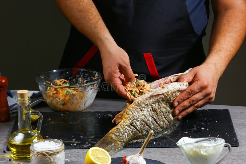 Men`s hands, close-up, holding river carp, Chef cooks fish with vegetables. healthy food, diet or cooking concept royalty free stock photo Men`s hands, close-up, holding river carp, Chef cooks fish with vegetables. healthy food, diet or cooking concept royalty free stock photo