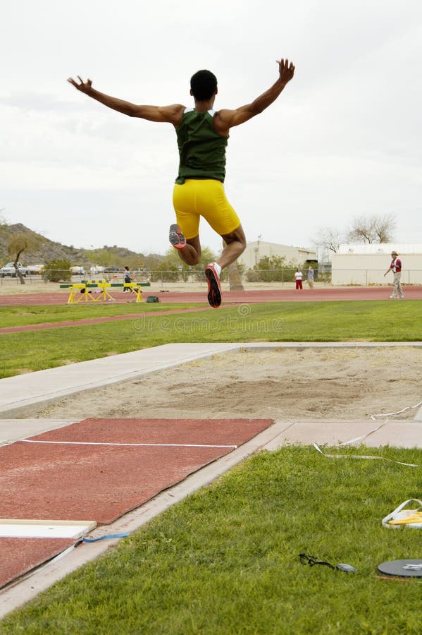 Un concorrente nella mens di salto in lungo, evento durante un college di atletica.