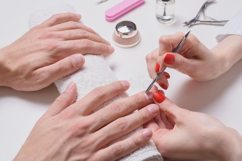 Men`s manicure. hands of the beautician treated cuticle of male hands using pusher, scraper