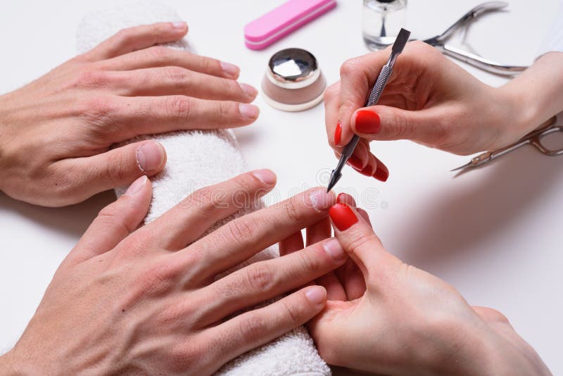 Men`s manicure. hands of the beautician treated cuticle of male hands using pusher, scraper