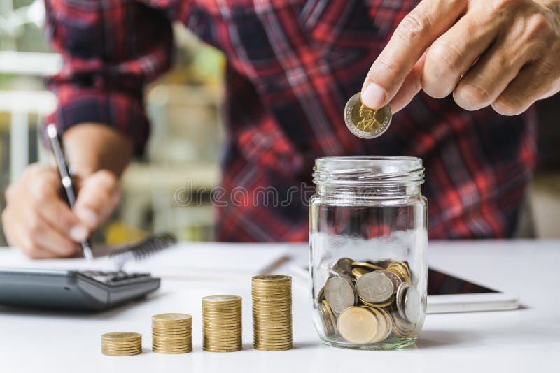 Men are Saint documents about save money and put coin in glass jar also have  calculator, coins on desk