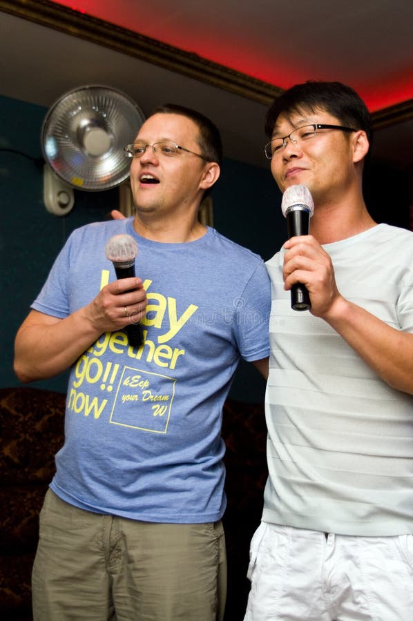 Two men singing karaoke together.