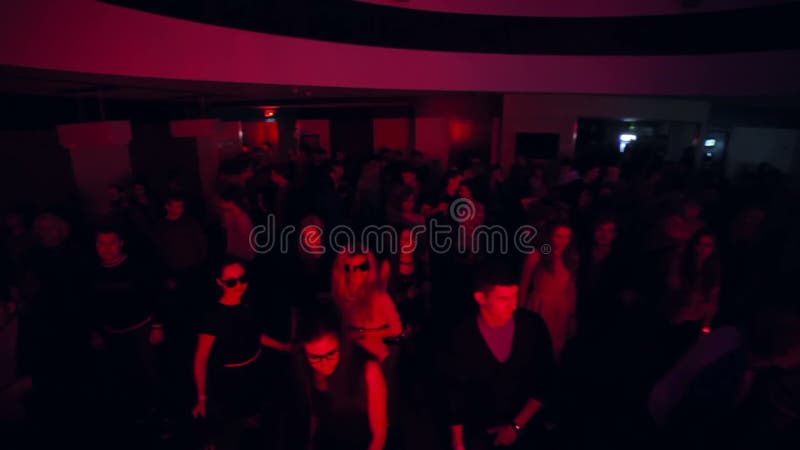 Men and women dance to sounds of music in night club. Jib shot