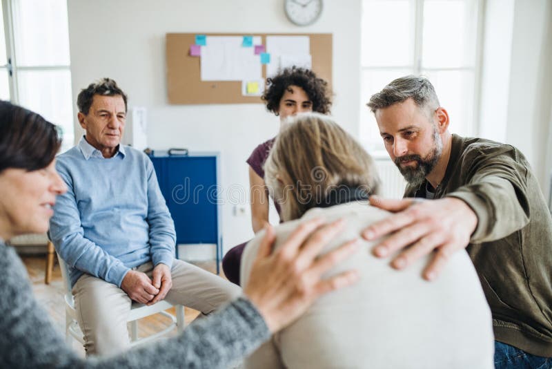 Men and women sitting in a circle during group therapy, supporting each other.