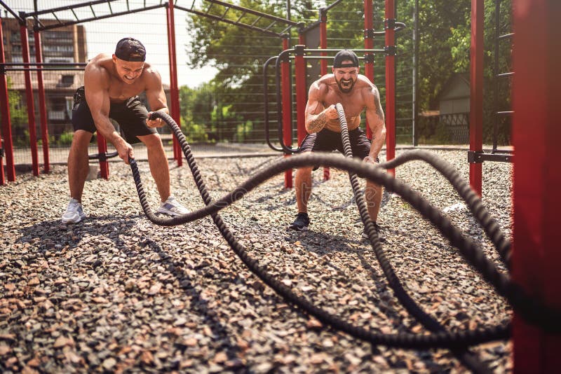 Men work hard with rope at street gym yard. Strength and motivation. Outdoor workout. fitness, sport, exercising stock photo Men work hard with rope at street gym yard. Strength and motivation. Outdoor workout. fitness, sport, exercising stock photo