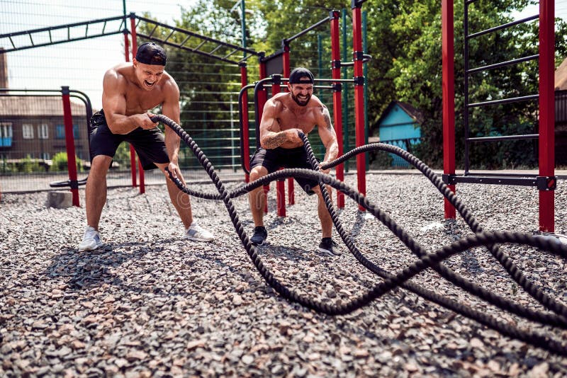 Men work hard with rope at street gym yard. Strength and motivation. Outdoor workout. fitness, sport, exercising stock photography Men work hard with rope at street gym yard. Strength and motivation. Outdoor workout. fitness, sport, exercising stock photography