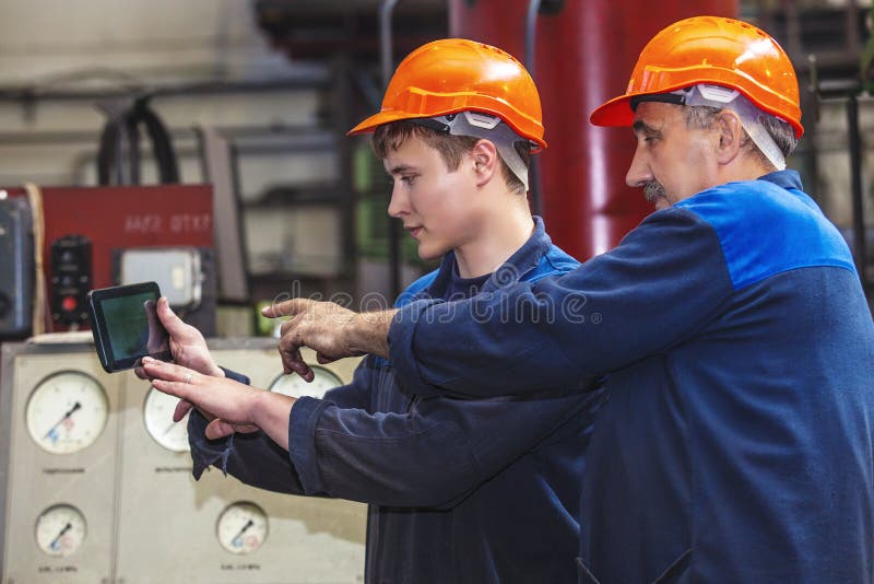 Men work on the old factory for the installation of equipment in protective helmets. Architect uniform stock images, royalty-free photos and pictures
