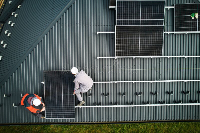 Men workers installing solar panels on roof of house. stock photo