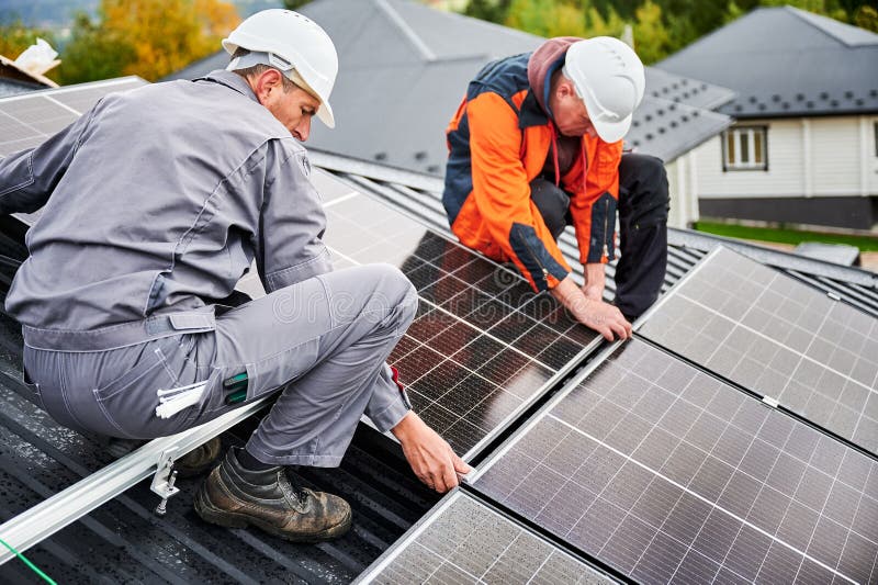 Men workers installing solar panels on roof of house. royalty free stock images