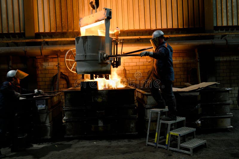 Men working with glowing molten hot steel. Steel casting.