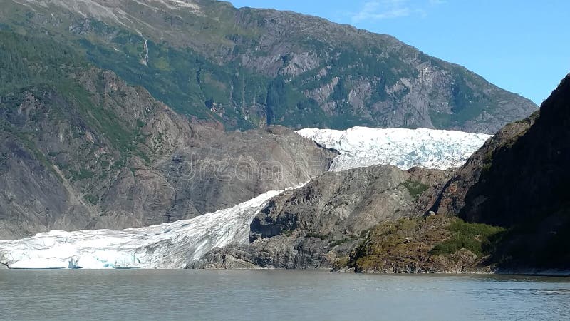 Mendenhall Glacier in Juneau Alaska. Large Glacier sliding into a lake with a waterfall beside it. Very popular tourist stop. A peaceful lake great for kayaking royalty free stock photography Mendenhall Glacier in Juneau Alaska. Large Glacier sliding into a lake with a waterfall beside it. Very popular tourist stop. A peaceful lake great for kayaking royalty free stock photography