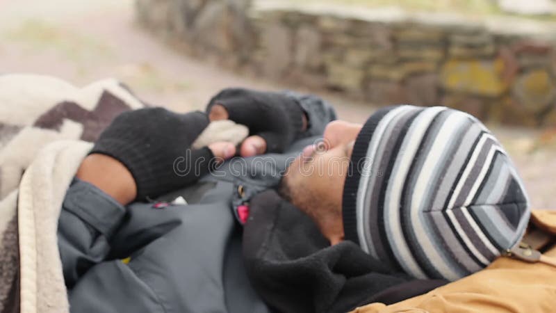 Mendiant masculin dormant sur le banc et se réveillant, phénomène des sans-abri, vivant dans la pauvreté