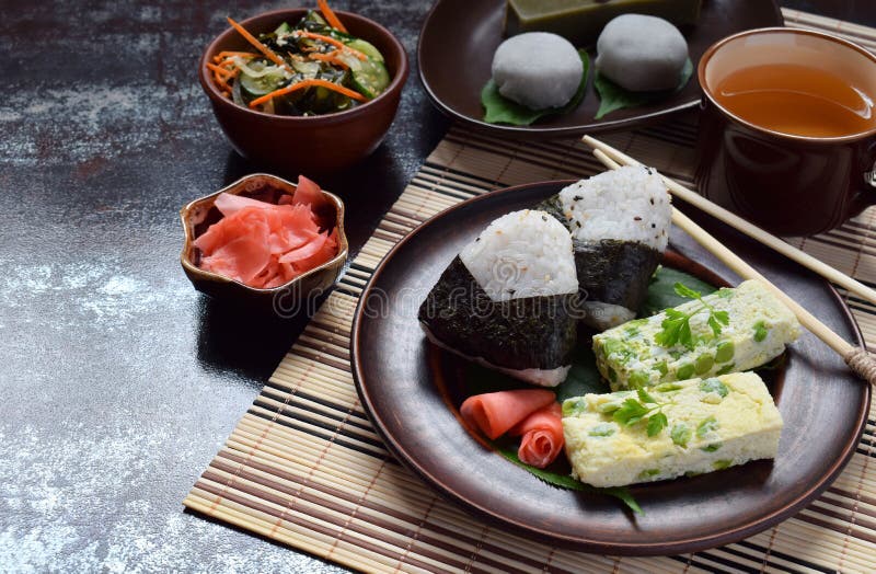 Mengeling van Japans voedsel - onigiri van rijstballen, omelet, gember, de salade van de sunomono wakame komkommer Traditioneel d stock foto Mengeling van Japans voedsel - onigiri van rijstballen, omelet, gember, de salade van de sunomono wakame komkommer Traditioneel d stock foto