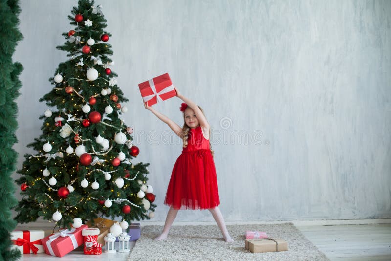 A menina abre presentes do Natal na casa de férias do ano novo de árvore de Natal foto de stock A menina abre presentes do Natal na casa de férias do ano novo de árvore de Natal foto de stock