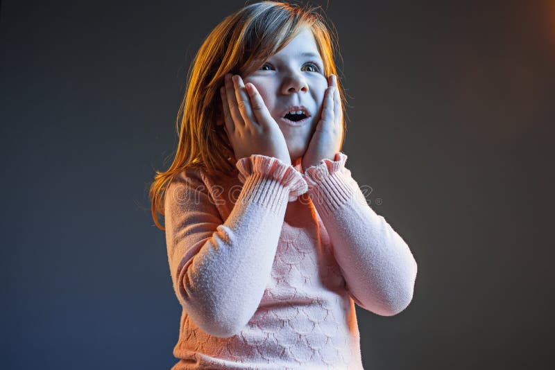A menina adolescente atrativa nova que olha surpreendida na obscuridade - azul imagem de stock A menina adolescente atrativa nova que olha surpreendida na obscuridade - azul imagem de stock