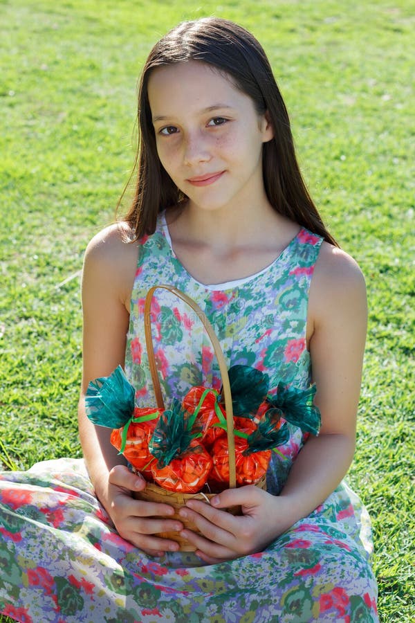 Menina adolescente bonito de sorriso que guarda a cesta com a cenoura do popco doce imagem de stock Menina adolescente bonito de sorriso que guarda a cesta com a cenoura do popco doce imagem de stock