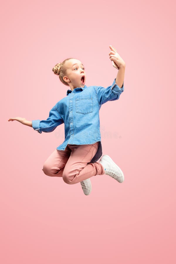 Menina adolescente caucasiano feliz nova que salta com o telefone no ar, isolado no fundo cor-de-rosa do estúdio imagens de stock Menina adolescente caucasiano feliz nova que salta com o telefone no ar, isolado no fundo cor-de-rosa do estúdio imagens de stock