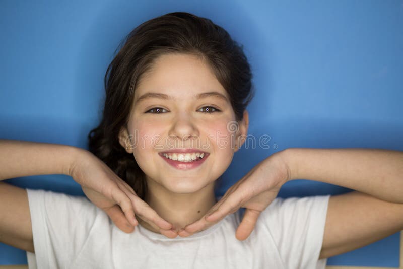 Menina adolescente de sorriso feliz bonita sobre o fundo azul foto de stock Menina adolescente de sorriso feliz bonita sobre o fundo azul foto de stock