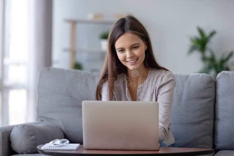 Menina adolescente de sorriso que usa o portátil para o estudo em linha em casa fotografia de stock royalty free Menina adolescente de sorriso que usa o portátil para o estudo em linha em casa fotografia de stock royalty free