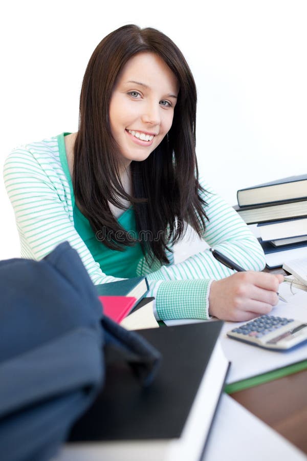 Menina adolescente feliz que estuda em uma mesa imagens de stock Menina adolescente feliz que estuda em uma mesa imagens de stock