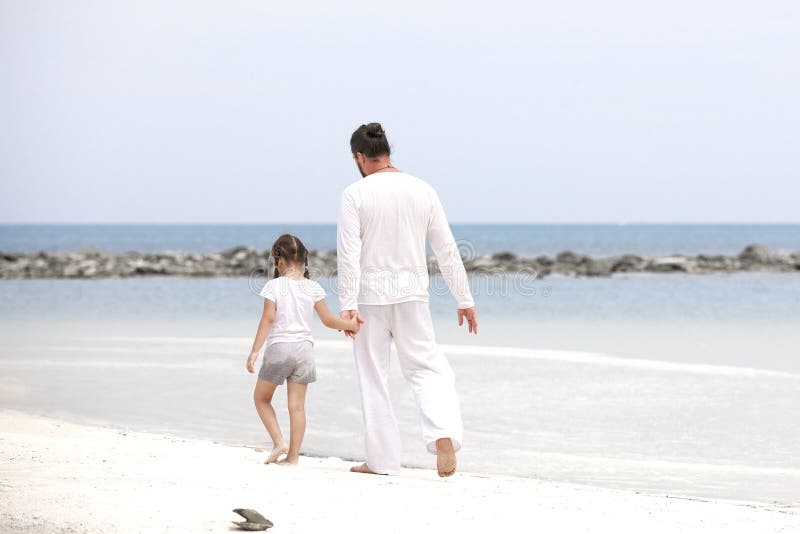 Menina adorável que guarda sua mão do pai Pai e filha que jogam junto na praia imagem de stock royalty free Menina adorável que guarda sua mão do pai Pai e filha que jogam junto na praia imagem de stock royalty free