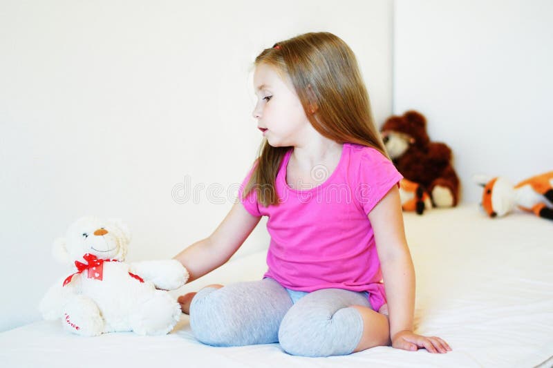 Menina adorável que joga com urso de peluche imagem de stock royalty free Menina adorável que joga com urso de peluche imagem de stock royalty free