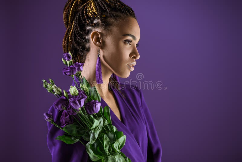 A menina afro-americano elegante que levanta com eustoma roxo floresce, imagem de stock royalty free A menina afro-americano elegante que levanta com eustoma roxo floresce, imagem de stock royalty free