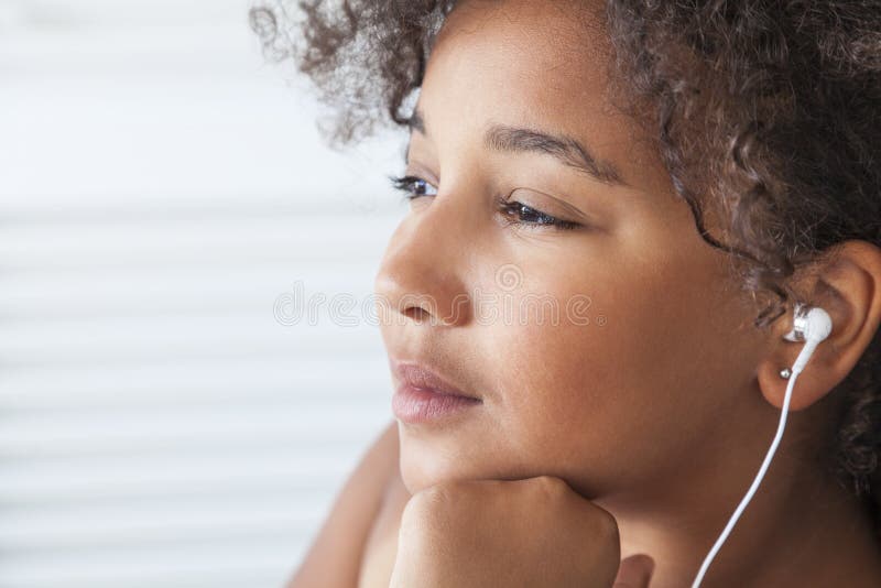 Menina afro-americano que escuta fones de ouvido da música MP3
