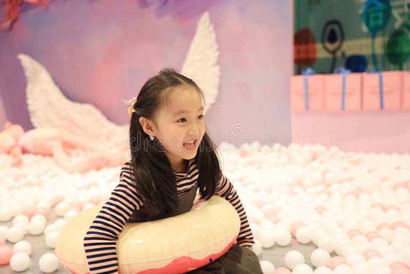 Menina alegre bonita que joga a terra de prazer no campo de jogos imagem de stock Menina alegre bonita que joga a terra de prazer no campo de jogos imagem de stock