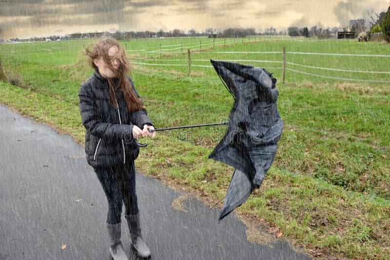 A menina anda através da chuva e a tempestade, seu guarda-chuva é quebrada A menina anda através da chuva e a tempestade, seu guarda-chuva é quebrada