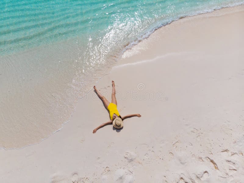 A menina apenas no litoral e aprecia o sol Jovem mulher em um chapéu de palha e em um roupa de banho amarelo imagem de stock A menina apenas no litoral e aprecia o sol Jovem mulher em um chapéu de palha e em um roupa de banho amarelo imagem de stock