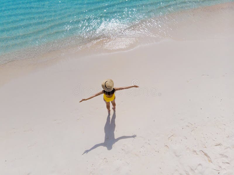A menina apenas no litoral e aprecia o sol Jovem mulher em um chapéu de palha e suportes amarelos do roupa de banho com os braços imagens de stock royalty free A menina apenas no litoral e aprecia o sol Jovem mulher em um chapéu de palha e suportes amarelos do roupa de banho com os braços imagens de stock royalty free