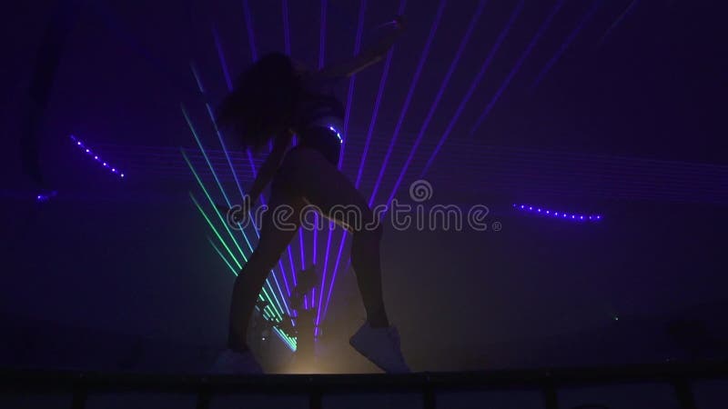 Menina apta que faz a ginástica com os lasers no fundo, movimento lento