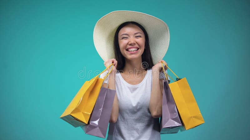 Menina asiática alegre em Panamá que guarda muitos sacos de papel, compra, o passatempo das mulheres