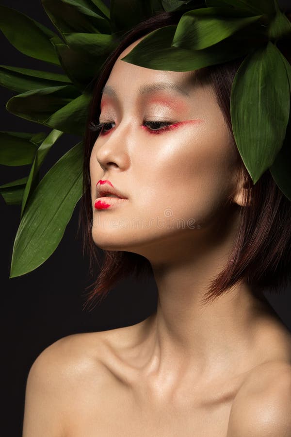 Menina asiática bonita com uma arte brilhante da composição nas folhas verdes Face da beleza Imagem creativa fotos de stock Menina asiática bonita com uma arte brilhante da composição nas folhas verdes Face da beleza Imagem creativa fotos de stock