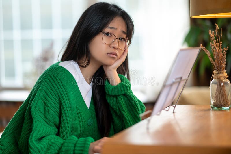 Menina asiática de cabelos longos sentada com um olhar infeliz imagens de stock