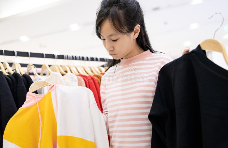 Menina asiática escolhendo roupas na loja de roupas no shopping center,as mulheres clientes comprando novas modas de manga longa imagem de stock Menina asiática escolhendo roupas na loja de roupas no shopping center,as mulheres clientes comprando novas modas de manga longa imagem de stock