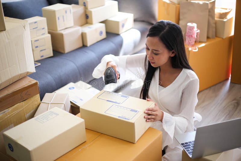A menina asiática nova é começo do freelancer acima do endereço pequeno da escrita do proprietário empresarial na caixa de cartão fotografia de stock A menina asiática nova é começo do freelancer acima do endereço pequeno da escrita do proprietário empresarial na caixa de cartão fotografia de stock