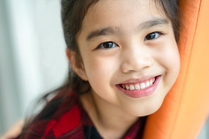 Menina asiática que sorri com sorriso perfeito e os dentes brancos nos cuidados dentários