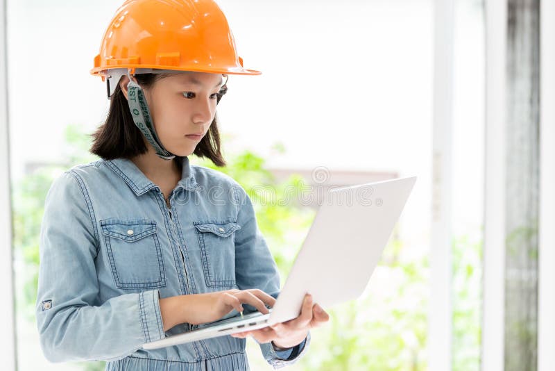 Menina asi?tica que veste o capacete ou o capacete de seguran?a alaranjado de seguran?a como o sonho do coordenador do arquiteto fotografia de stock Menina asi?tica que veste o capacete ou o capacete de seguran?a alaranjado de seguran?a como o sonho do coordenador do arquiteto fotografia de stock