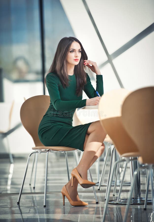 Menina atrativa no vestido verde que senta-se na escrita da cadeira fotos de stock Menina atrativa no vestido verde que senta-se na escrita da cadeira fotos de stock