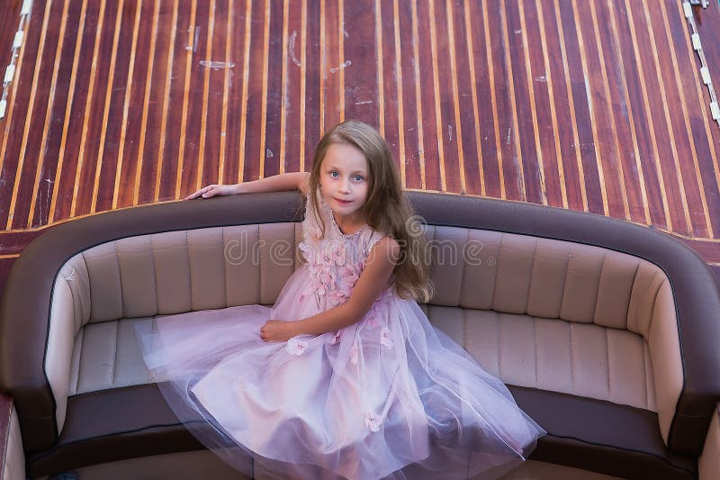 A menina bonita bonito com cabelo longo senta-se no barco Princesa da menina imagens de stock A menina bonita bonito com cabelo longo senta-se no barco Princesa da menina imagens de stock