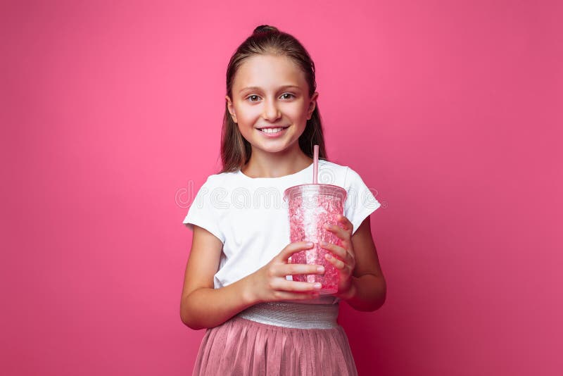 Menina bonita com uma bebida ou cocktail em suas mãos, em um fundo cor-de-rosa, em um estúdio da foto, close-up fotografia de stock Menina bonita com uma bebida ou cocktail em suas mãos, em um fundo cor-de-rosa, em um estúdio da foto, close-up fotografia de stock