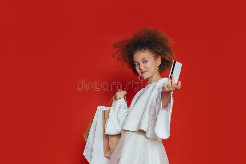 Menina bonita de sorriso com cabelo encaracolado e compra em um fundo vermelho imagens de stock royalty free Menina bonita de sorriso com cabelo encaracolado e compra em um fundo vermelho imagens de stock royalty free