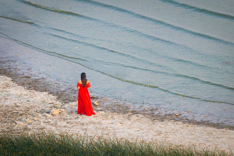 Beautiful girl in a long red dress. Concept of femininity, harmony or waiting her man. Beautiful girl in a long red dress. Concept of femininity, harmony or waiting her man