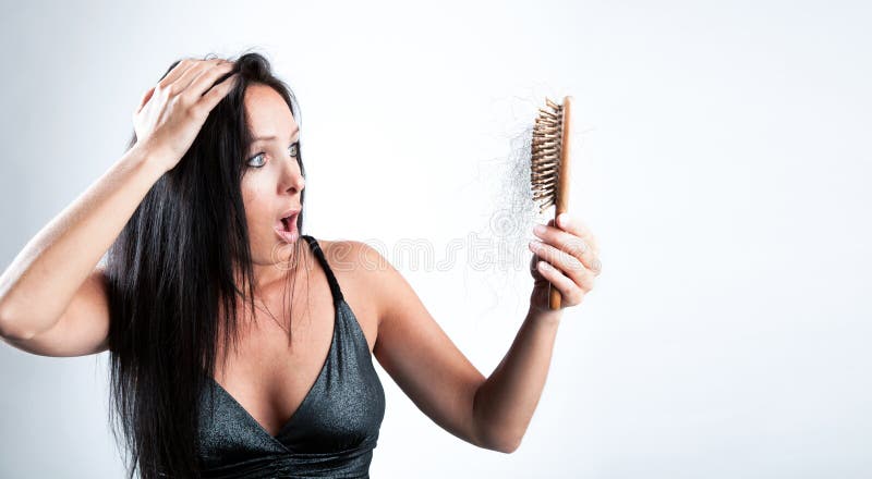 A menina bonita está olhando chocou-se a sua escova de cabelo foto de stock A menina bonita está olhando chocou-se a sua escova de cabelo foto de stock