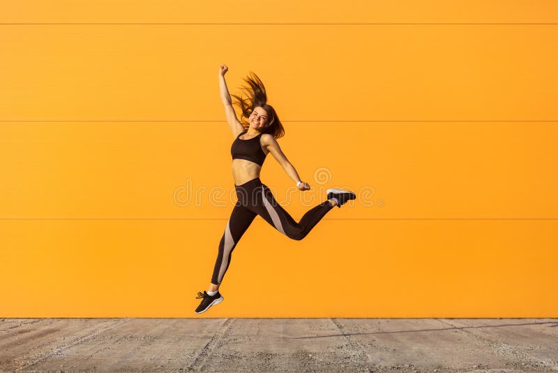 A menina bonita feliz nova que veste exercícios praticando do esporte do sporwear preto na manhã na rua, comemora o resultado do fotografia de stock royalty free A menina bonita feliz nova que veste exercícios praticando do esporte do sporwear preto na manhã na rua, comemora o resultado do fotografia de stock royalty free