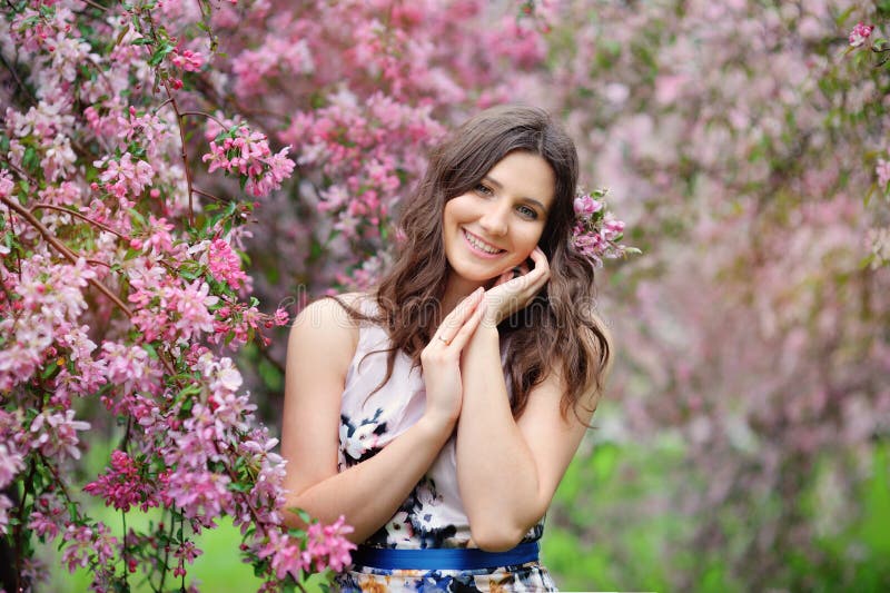 Menina bonita no jardim da mola entre as árvores de florescência imagem de stock Menina bonita no jardim da mola entre as árvores de florescência imagem de stock