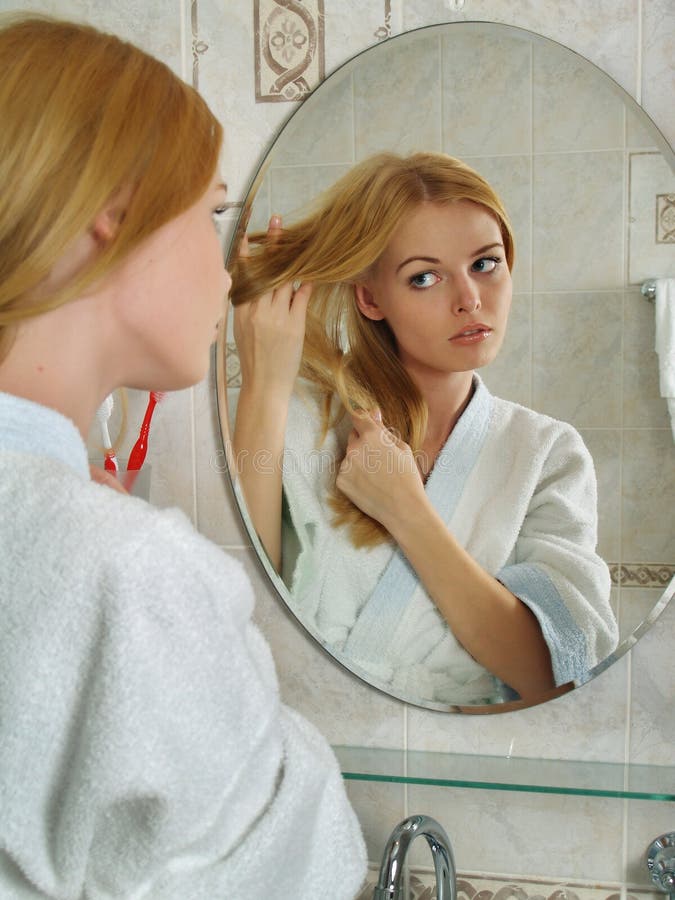 A Menina Bonita Olha Em Um Espelho Em Um Banheiro Foto de Stock - Imagem de  cara, adulto: 13967092